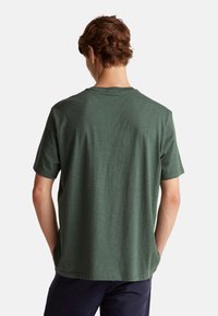 Zelené tričko s krátkým rukávem a kulatým výstřihem. Měkká, strukturovaná látka. Jednoduchý design bez viditelných vzorů nebo akcentů. Volný střih.