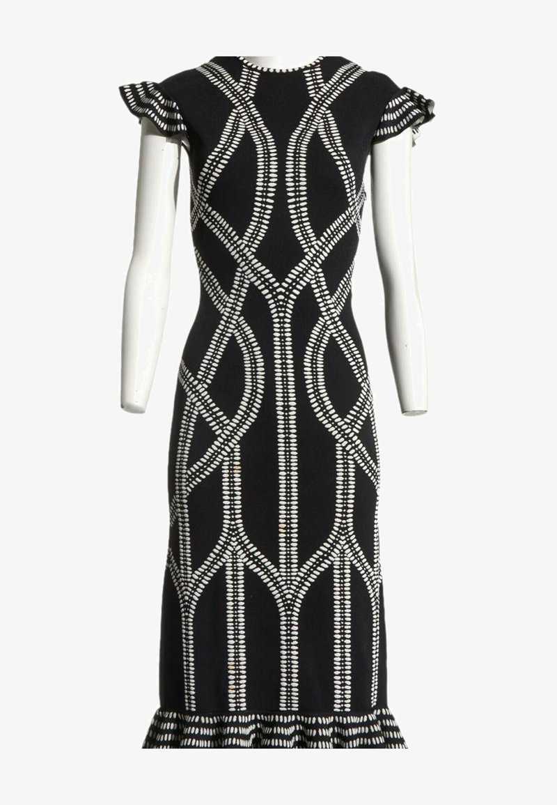 Robe noire cintrée avec des motifs géométriques blancs à pois, manches courtes volantées et ourlet à volants, exposée sur un mannequin blanc.
