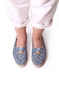Blauwe florale espadrilles met een geweven jute zool, voorzien van een plat ontwerp en lichtblauwe accenten bij de openingsrand en een klein bruin leren detail.