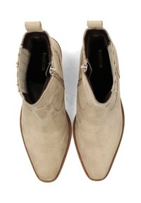Stivali ankle in suede beige con punta affusolata, cerniere laterali e un accento testurizzato lungo il colletto. Suole simili al legno e design minimale.