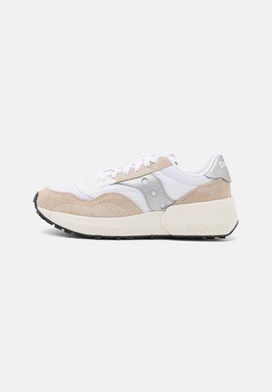 Baskets pour hommes beiges et blanches Saucony avec des empiècements en daim, des lacets blancs et une épaisse semelle blanc cassé sur un fond blanc uni.
