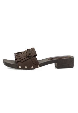 Zueco de ante marrón con puntera abierta, tacón grueso, detalle de flecos y lazo, y tachuelas metálicas a lo largo de la correa lateral.