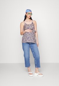 Top de alças com estampado floral, com detalhe de nó na frente, combinado com jeans de pernas retas azul claro e sandálias brancas de plataforma.