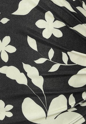 Sort stof med en blank overflade, der har store hvide blomster- og bladmønstre, hvilket skaber kontrast og visuel interesse.