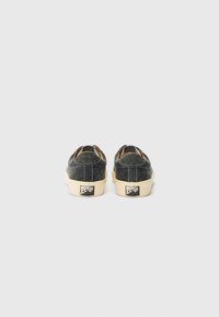 Scarpe slip-on in denim grigio con suola in gomma, caratterizzate da cuciture bianche a contrasto e un logo sul tallone. Design con punta arrotondata.