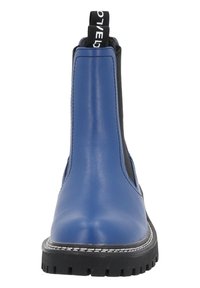 Botas Chelsea de cuero azul con paneles laterales elásticos negros, tirador y costuras blancas en contraste. Suela de goma negra gruesa y texturizada.