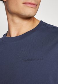 Marineblå bomull T-skjorte med rund hals og subtilt brodert logo på brystet. Glatt tekstur og tettsittende design.