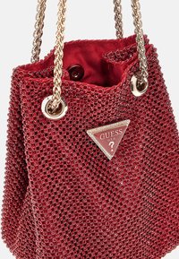Borsa a secchiello in velluto rosso con hardware argentato, caratterizzata da un esterno testurizzato con embellishments circolari e una placca con logo sulla parte anteriore.