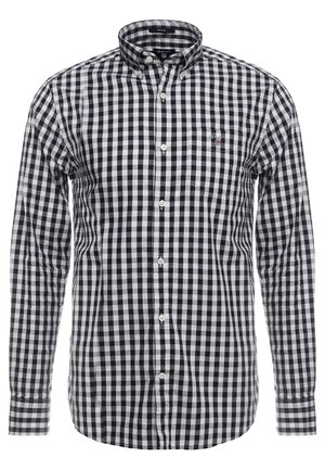 Camisa de manga larga a cuadros en blanco y negro, con botones, bolsillo en el pecho y cuello abotonado.