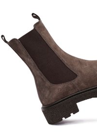 Botín Chelsea de ante marrón con paneles laterales elásticos, tiradores y una suela de goma texturizada que proporciona un mayor agarre y flexibilidad.