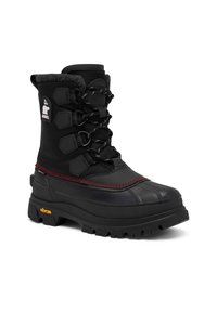 Botte d'hiver noire avec une tige texturée, un point de surpiqûre rouge, un embout renforcé et une semelle Vibram antidérapante. Dotée de lacets ajustables.