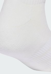 Calcetín blanco hasta el tobillo hecho de tela suave y texturizada con un patrón acanalado para mayor elasticidad. Presenta áreas reforzadas en el talón y la punta para mayor durabilidad.