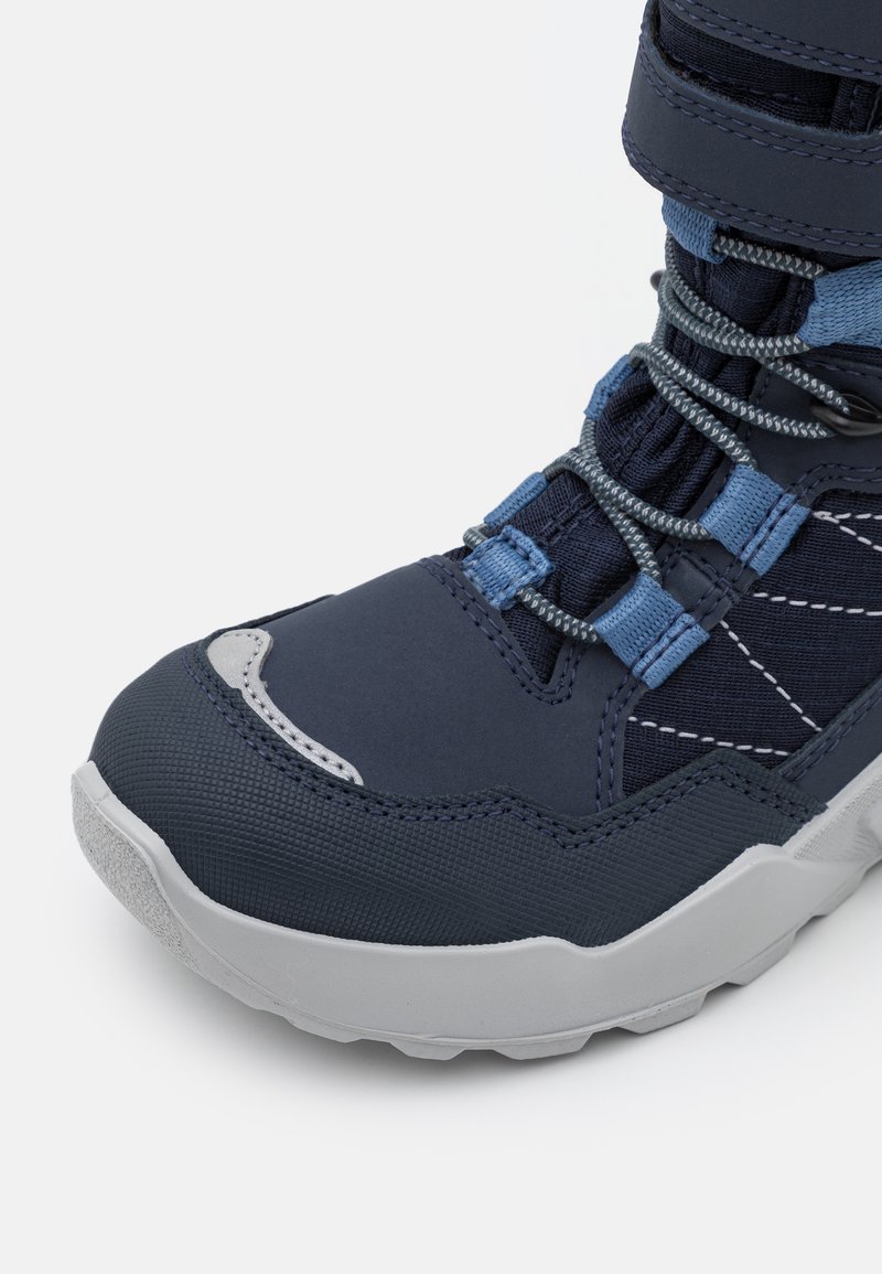 Marineblaue Wanderschuhe mit strukturiertem Obermaterial, grauen Akzenten, Schnürsenkeln, die durch einen Stopper gesichert sind, und einer dicken grauen Gummisohle für besseren Halt.