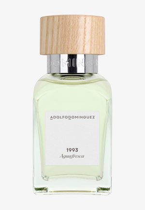 Flacon de parfum en verre avec un liquide vert pâle, bouchon en bois et étiquette indiquant « Adolfo Dominguez 1993 Aguafresca ».
