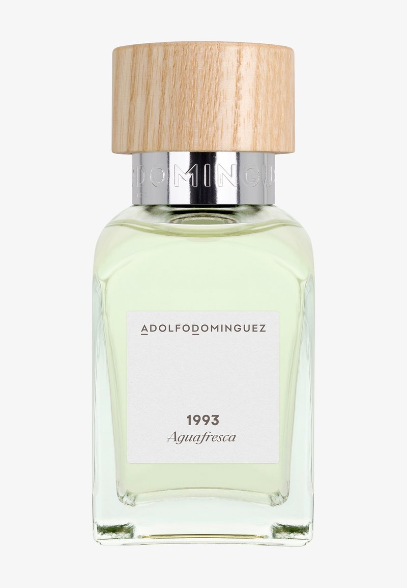 Flacon de parfum en verre avec un liquide vert pâle, bouchon en bois et étiquette indiquant « Adolfo Dominguez 1993 Aguafresca ».