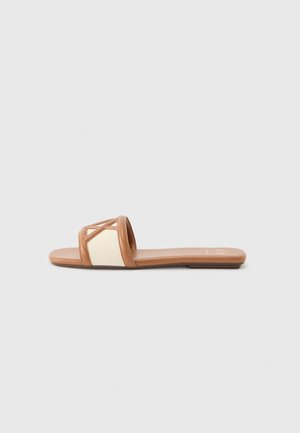 Platte slippers met een tanleren zool en brede beige stoffen band met bruine leren afwerking en geometrisch uitgesneden ontwerp.