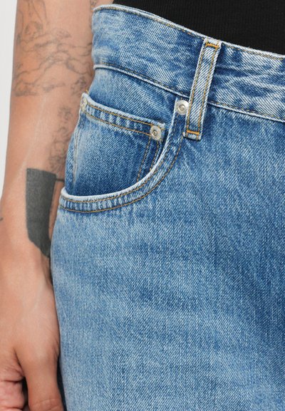 Jeans de ganga azul-claro com cintura alta, apresentando design clássico de cinco bolsos, costura laranja em contraste e detalhe de botão de metal.