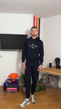 Marineblauw hoodie- en joggingbroekset met het "Tommy Hilfiger" logo. Hoodie heeft een kangoeroezak; broek heeft elastische boorden. Zilveren en zwarte sneakers.