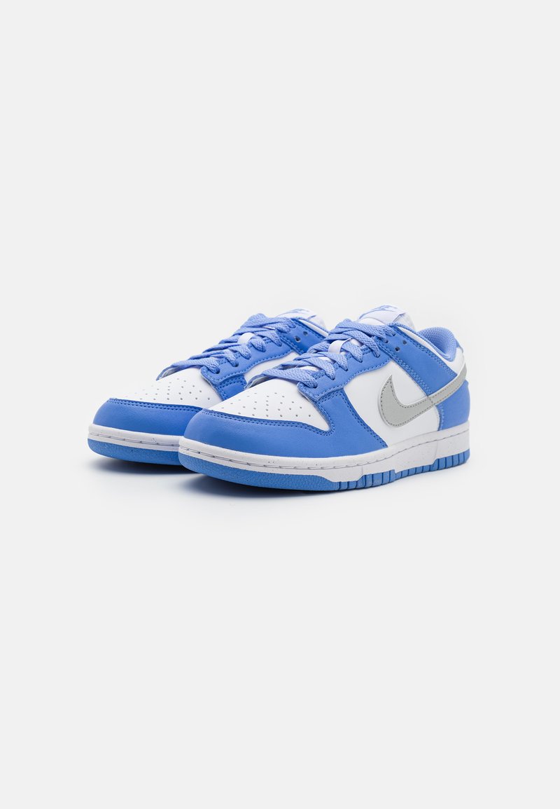 Sneaker in pelle blu con una punta bianca, dettagli azzurri e il logo Nike grigio. Superficie testurizzata con perforazioni sul davanti.