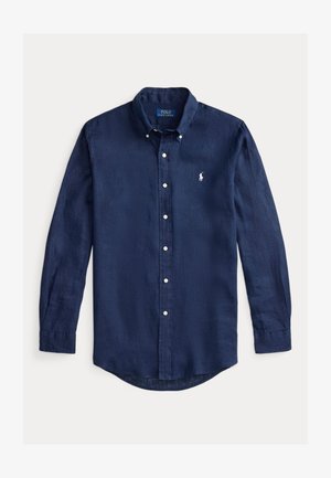 Pusmūksnas zila garo piedurkņu pogājama krekliņa vieglā audumā ar noapaļotu apakšmalu un mazu izšūtu logotipu krūtīs.