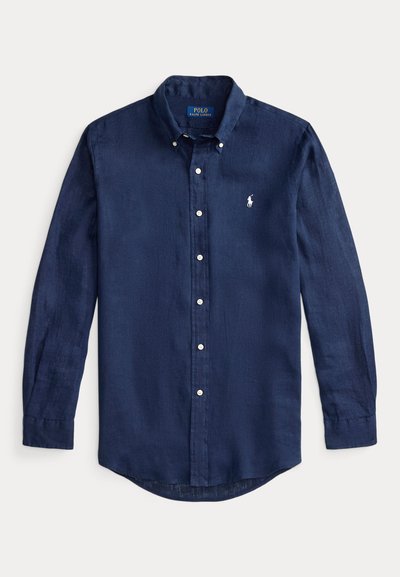 Pusmūksnas zila garo piedurkņu pogājama krekliņa vieglā audumā ar noapaļotu apakšmalu un mazu izšūtu logotipu krūtīs.