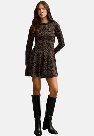 Bruine lange mouwen jurk met een luipaardprint, uitlopende rok en aansluitend bovenlijfje. Gecombineerd met kniehoge zwarte laarzen.