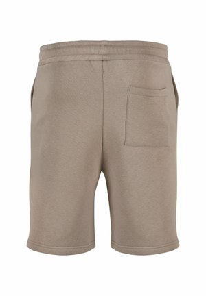 Beige pamut sort, rugalmas derékkal, egy hátsó zsebbe és sima felületbe ágyazva. A szegések letisztultak és egyszerűek.