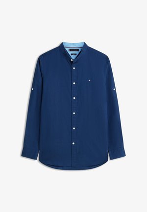 Hosszú ujjú tengerészkék gombos ing szalaggal záródó gallérral, fehér gombokkal és a mellkason kis hímzett logóval.