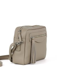 Borsa a tracolla in pelle beige con superficie testurizzata, dotata di una tasca con zip frontale e un accento con nappina. Cinghia regolabile inclusa.