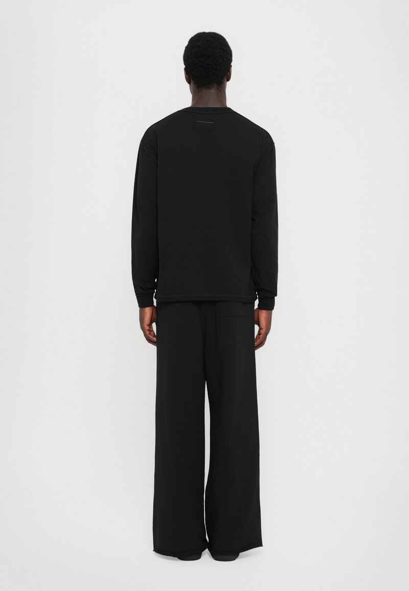 Chemise noire à manches longues et pantalon à jambes larges. Matière en coton. Design simple avec des lignes épurées. Pas de marque ou d'embellissements visibles.