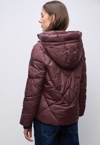Bordeauxfarbene Pufferjacke mit Kapuze, ausgestattet mit einem Rautenmuster und einem kleinen Logo-Patch am Ärmel. Glattes, glänzendes Material, isoliert.