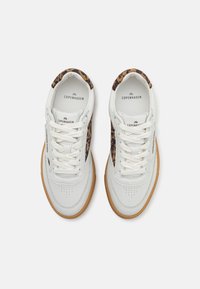 Paire de baskets en cuir blanc avec des accents imprimé léopard, semelles en gomme et lacets blancs, marquées "Copenhagen Studios" à l’intérieur et sur les côtés.