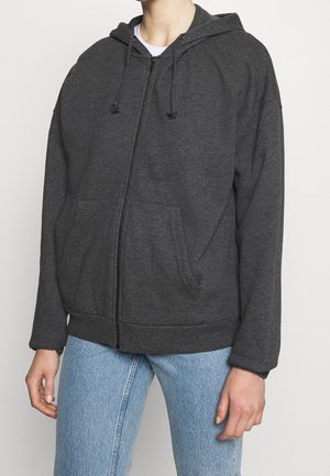 Felpa grigia con zip, cappuccio regolabile, tasche frontali e orlo a costine. Il tessuto sembra morbido e strutturato, adatto per un abbigliamento casual.