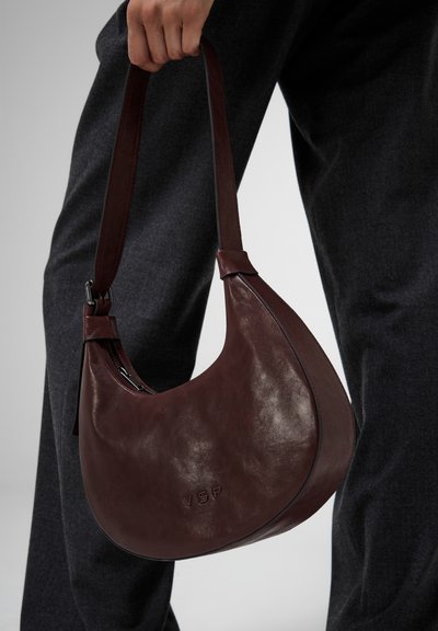 Borsa a tracolla in pelle bordeaux con design curvo, tracolla e chiusura con zip; logo 'VSP' in rilievo sul davanti.