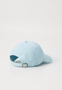 Casquette de baseball en coton bleu clair avec une visière incurvée, une sangle réglable à l'arrière et une texture douce. Aucun logo ou motif visible.