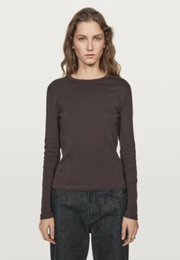 Langærmet brun skjorte lavet af blødt stof med rund halsudskæring. Tæt pasform, glat struktur, ensfarvet design, sammen med mørke jeans.