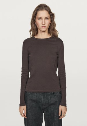 Braunes Langarmhemd aus weichem Stoff mit Rundhalsausschnitt. Figurbetonte Silhouette, glatte Textur, schlichtes Design, kombiniert mit dunklen Jeans.