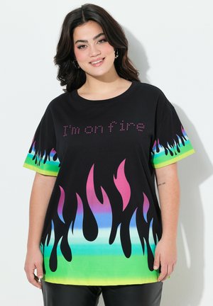 T-shirt nera oversize con stampa di fiamme colorate in rosa, blu e verde, con il testo "I'm on fire" in design con borchie sul fronte.