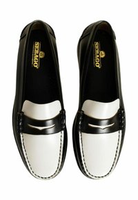Mocassini in pelle bianca e nera con un design a profilo basso, cuciture decorative a sella e un accentuato dettaglio nero texturizzato sulla parte anteriore.