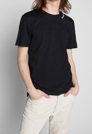 Schwarzes T-Shirt mit kurzen Ärmeln und klarem Design, mit horizontaler Naht über der Brust und kleinem Logo auf der Schulter.