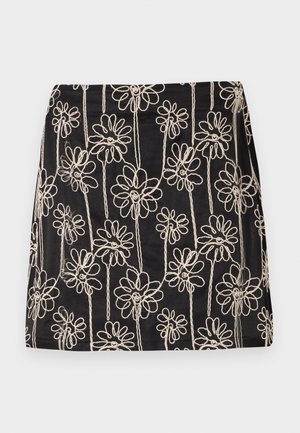 Svart kjol med vit blomsterbroderi och slingrande mönster. Slät textur och figurnära passform, med synliga söm detaljer.