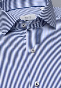 Blauw en wit gestreept overhemd met een button-down kraag, lichte stof en plastic knopen; etiket zichtbaar binnenin de kraag.
