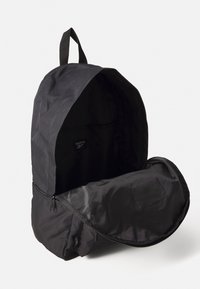 Schwarzer Rucksack aus strapazierfähigem Gewebe. Verfügt über ein Hauptfach mit Reißverschluss und eine Vordertasche, sowie einen geschlungenen Griff oben.