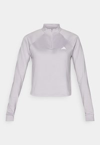 Vaalean violetti urheilullinen pitkähiha-paita, jossa on puolivetoketjullinen kaulus, raglansovitukset ja pieni valkoinen logo rinnassa.