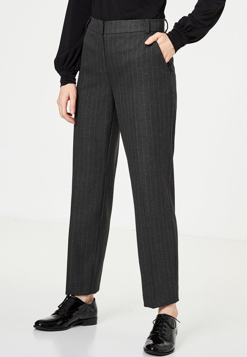 Šedé proužkované kalhoty s rovnými nohavicemi, vyrobené z texturované látky. Obsahují boční kapsy a plochý pas, v kombinaci s černými botami.