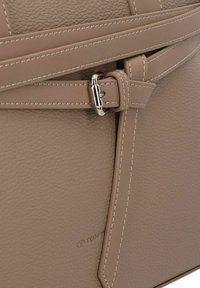 Beige leren handtas met een gestructureerd oppervlak, smalle banden met een zilveren metalen gesp en contrasterende stikdetails.