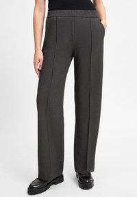 Dark gray, wide-leg trousers made from textured fabric, featuring a high waist and side pockets, paired with black platform shoes.