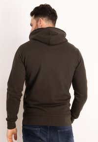 Felpa verde scuro con una consistenza morbida, caratterizzata da un grande cappuccio accogliente, polsini e vita a costine. La vista posteriore evidenzia il design senza cuciture.