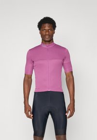 Kurzärmliges Fahrradtrikot in leuchtendem Pink mit durchgehendem Reißverschluss und Stehkragen, kombiniert mit schwarzen gepolsterten Shorts. Glatte Textur.