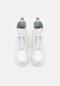 Weiße High-Top-Schuhe aus glänzendem Material mit einer glatten Textur, ausgestattet mit weißen Schnürsenkeln und einem weichen grauen Innenfutter.